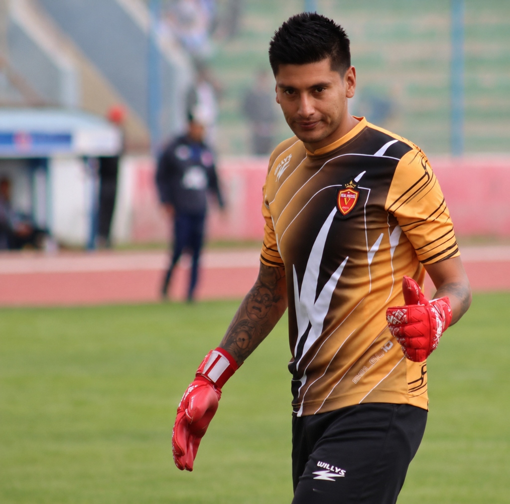Christian Salinas sonriendo en el campo de juego con sus guantes de guardameta